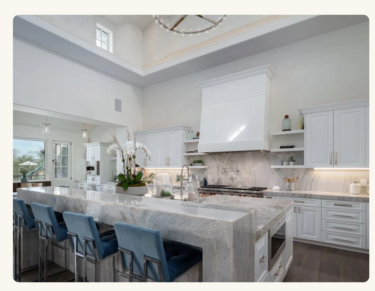 White kitchen with marble island and blue velvet bar stools