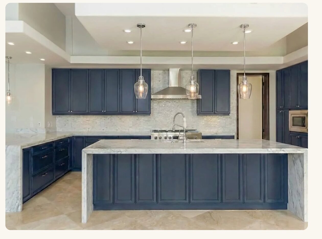 Navy blue kitchen with marble island and pendant lights
